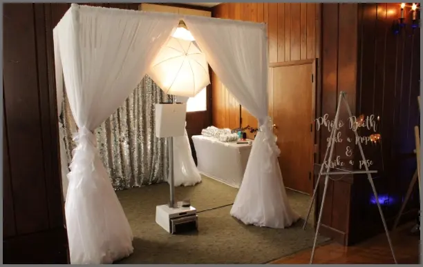 Elegant white sheer fabric canopy surrounding photo booth